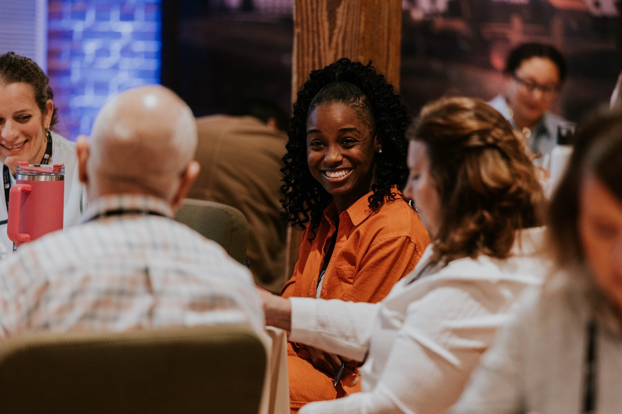 Nonprofit leader laughing and connecting with peers during a WinShape Leadership Collective, diverse group around the table
